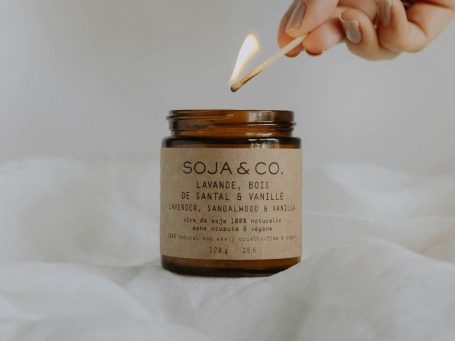 Symbolfoto Kerze Braune Duftkerze mit angezündetem Streichholz.