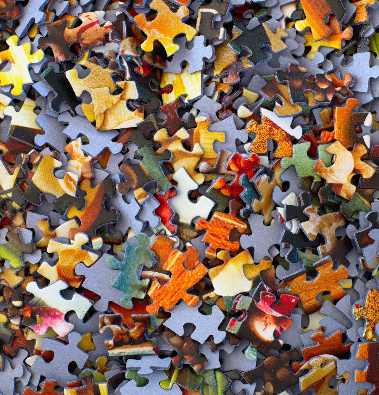 Bunte Puzzle-Teile liegen chaotisch auf einem Tisch verstreut.